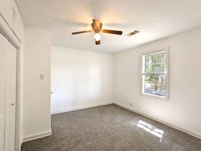 unfurnished bedroom featuring dark colored carpet, ceiling fan, a textured ceiling, and a closet