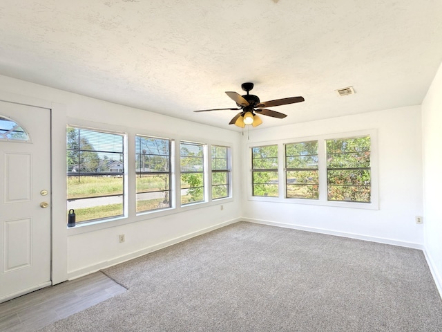 carpeted empty room with ceiling fan and a textured ceiling