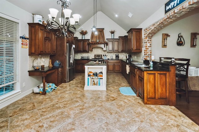 kitchen featuring stainless steel refrigerator with ice dispenser, custom range hood, sink, decorative light fixtures, and a notable chandelier