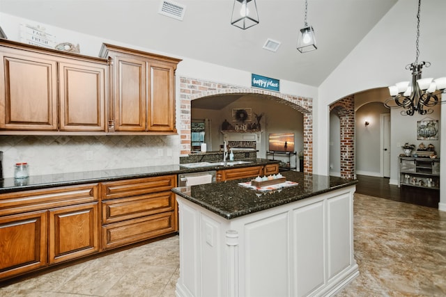 kitchen with sink, high vaulted ceiling, a notable chandelier, backsplash, and pendant lighting