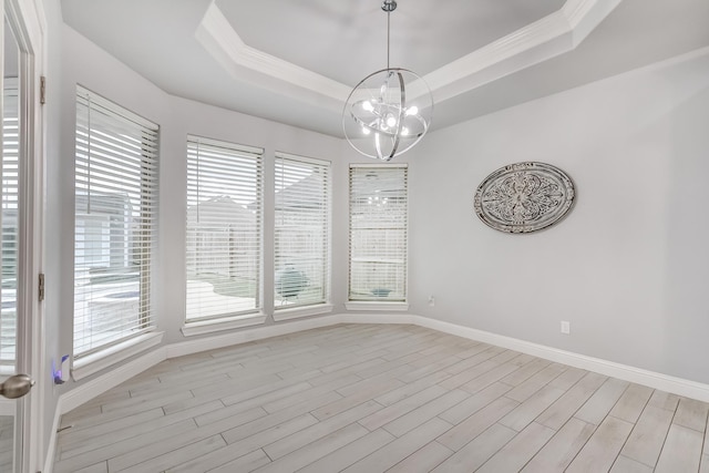 unfurnished dining area featuring crown molding, a raised ceiling, light hardwood / wood-style flooring, and a chandelier