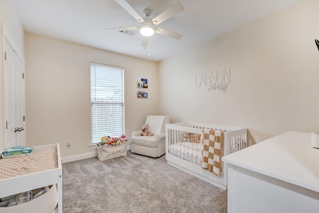 bedroom featuring ceiling fan, light carpet, and a crib