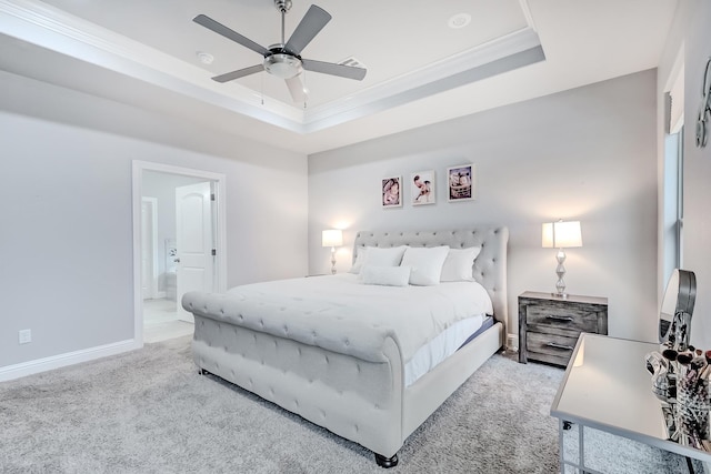 carpeted bedroom featuring ceiling fan, crown molding, ensuite bathroom, and a raised ceiling