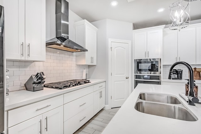 kitchen featuring white cabinets, appliances with stainless steel finishes, wall chimney exhaust hood, and sink