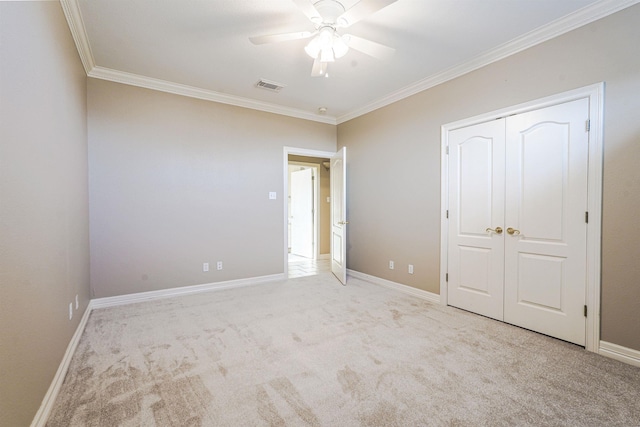 unfurnished bedroom with a closet, light colored carpet, ceiling fan, and ornamental molding