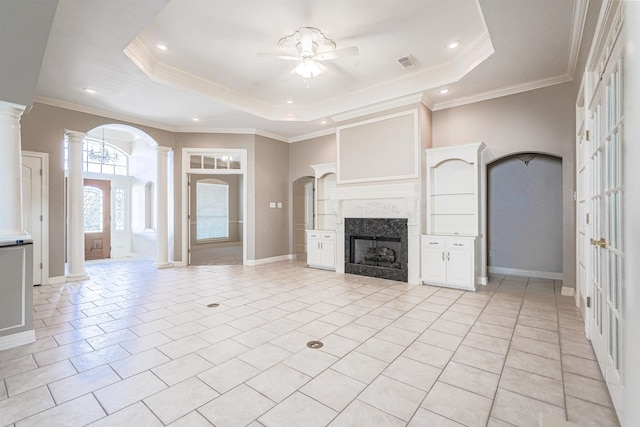 unfurnished living room with decorative columns, a tray ceiling, ceiling fan, crown molding, and light tile patterned floors