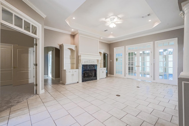 unfurnished living room with a raised ceiling, french doors, light tile patterned floors, and ornamental molding