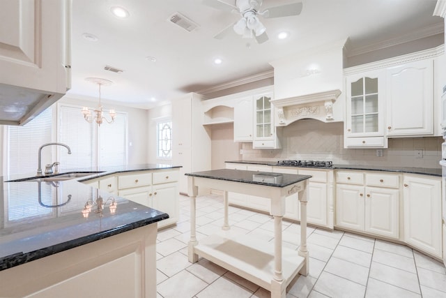 kitchen with decorative light fixtures, white cabinetry, a kitchen island, and sink