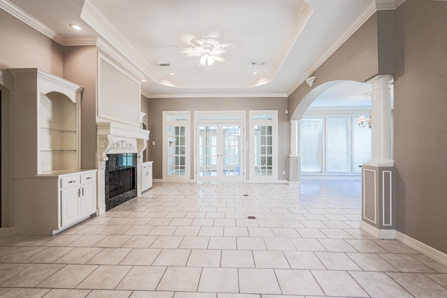 unfurnished living room featuring crown molding, ceiling fan, a premium fireplace, light tile patterned floors, and a tray ceiling