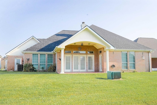 rear view of property with a lawn, central AC, and french doors