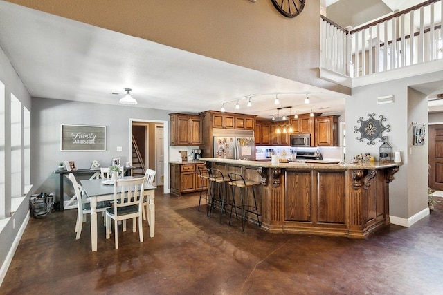 kitchen featuring a breakfast bar, decorative light fixtures, kitchen peninsula, and appliances with stainless steel finishes