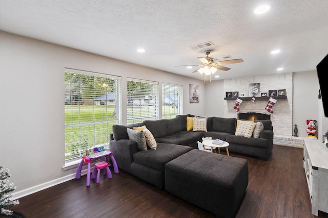 living room with a textured ceiling, a wealth of natural light, dark wood-type flooring, and ceiling fan