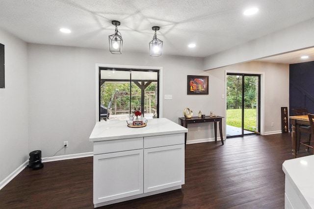 kitchen featuring a textured ceiling, white cabinets, hanging light fixtures, and dark hardwood / wood-style floors