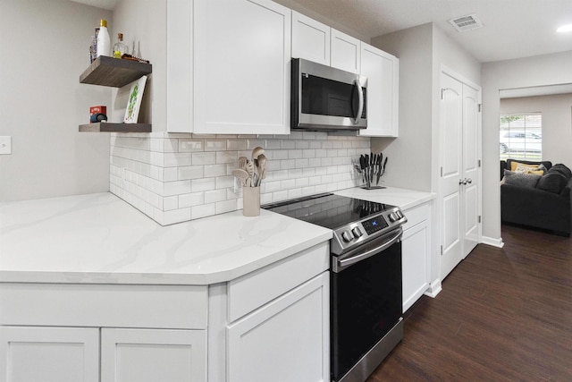 kitchen featuring light stone countertops, dark wood-type flooring, decorative backsplash, white cabinets, and appliances with stainless steel finishes