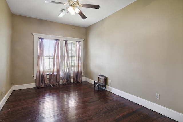 spare room with ceiling fan, a wood stove, and dark hardwood / wood-style floors