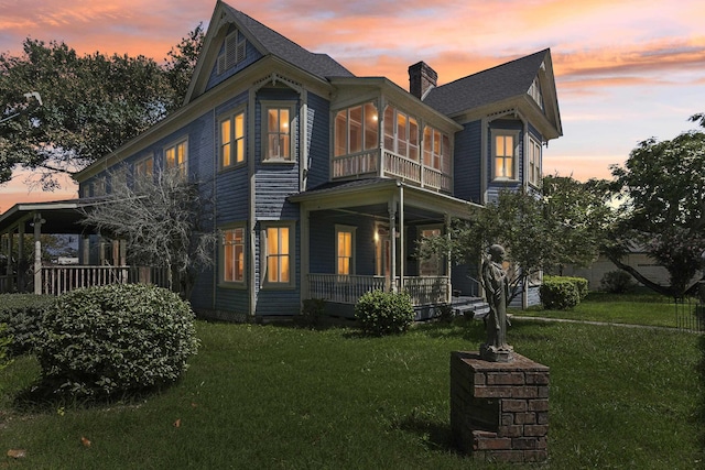 view of front of house with a sunroom, a lawn, and a porch