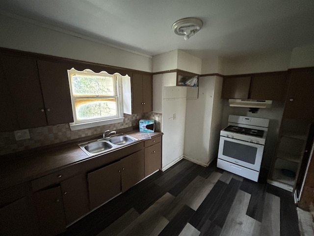 kitchen with white gas stove, backsplash, dark brown cabinetry, and sink