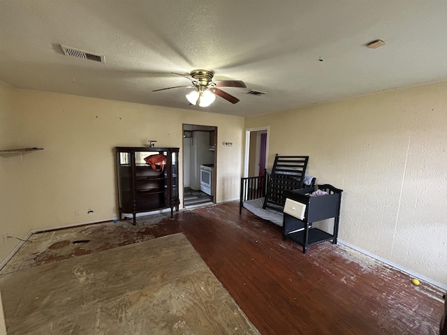 misc room with a textured ceiling, dark wood-type flooring, and ceiling fan