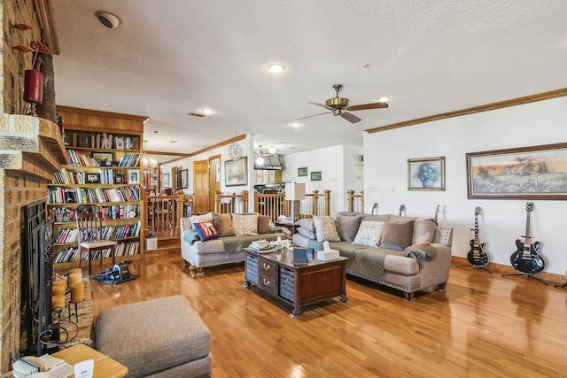 living room featuring ceiling fan, light hardwood / wood-style floors, ornamental molding, and a textured ceiling