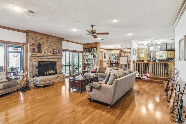 living room featuring a brick fireplace, ornamental molding, a textured ceiling, ceiling fan with notable chandelier, and hardwood / wood-style flooring