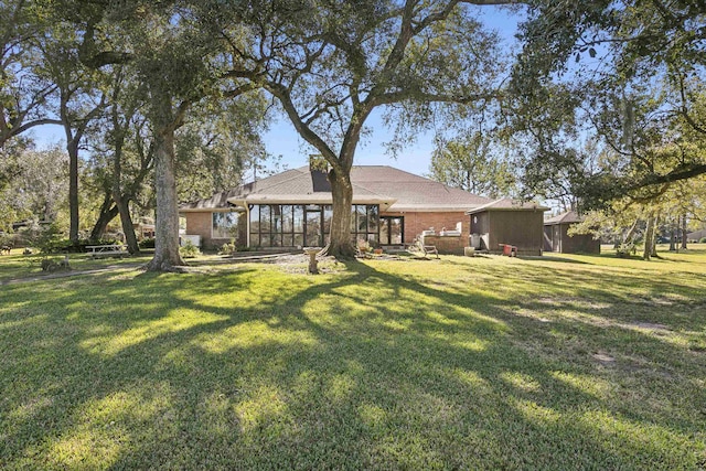 rear view of house with a sunroom and a lawn