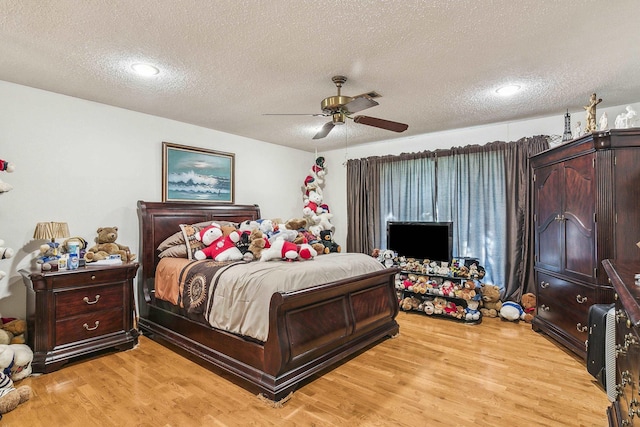 bedroom featuring ceiling fan, a textured ceiling, and light hardwood / wood-style flooring