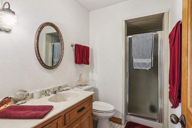 bathroom with tile patterned floors, vanity, toilet, and a shower with shower door