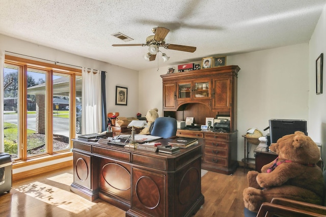 office area featuring a textured ceiling, dark hardwood / wood-style flooring, ceiling fan, and a healthy amount of sunlight