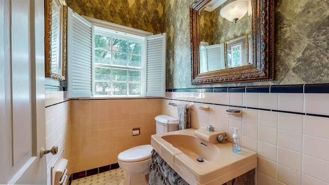 bathroom featuring toilet, tile walls, and sink