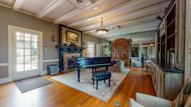 misc room with a tile fireplace, beam ceiling, and hardwood / wood-style floors