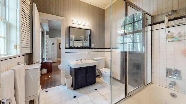 full bathroom with vanity, combined bath / shower with glass door, tile patterned flooring, toilet, and tile walls