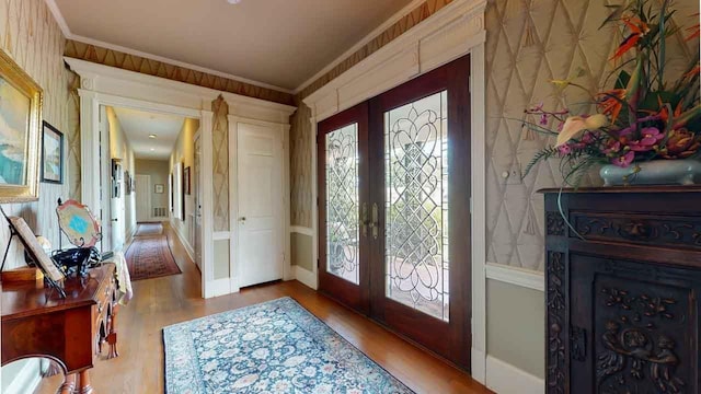 entrance foyer featuring french doors, light hardwood / wood-style flooring, and crown molding