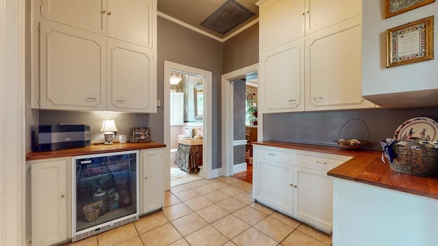 kitchen with white cabinetry, wine cooler, wooden counters, light tile patterned floors, and ornamental molding