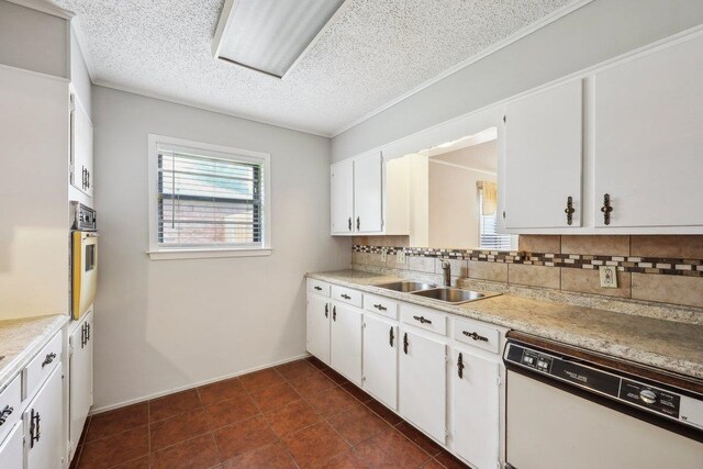 5960 Navajo Trl, Beaumont, TX 77708 - kitchen with white dishwasher, a sink, tasteful backsplash, white cabinetry, and a textured ceiling