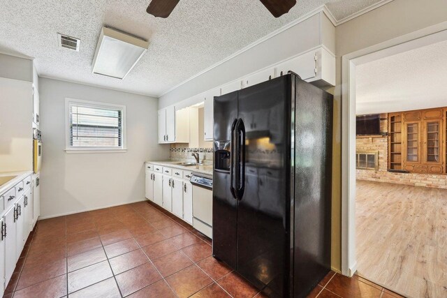 5960 Navajo Trl, Beaumont, TX 77708 - kitchen with black fridge, dishwasher, light countertops, white cabinetry, and a textured ceiling
