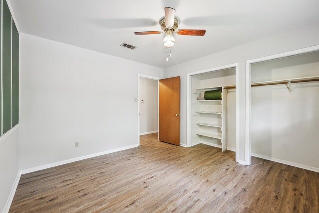 5960 Navajo Trl, Beaumont, TX 77708 - unfurnished bedroom with two closets, wood finished floors, baseboards, and a ceiling fan
