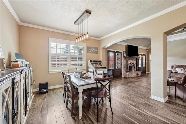 3113 Labrador Ln, Port Neches, TX 77651 - dining space with wood finished floors, a fireplace, baseboards, a textured ceiling, and arched walkways