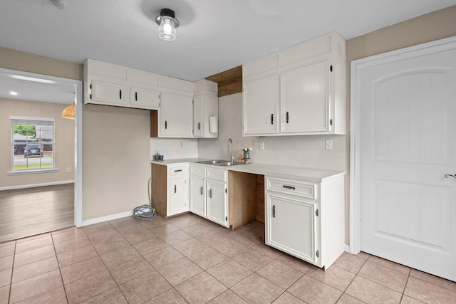 kitchen featuring light countertops, light tile patterned flooring, white cabinetry, and a sink
