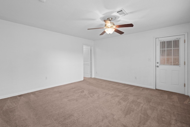 carpeted spare room with visible vents, baseboards, and ceiling fan