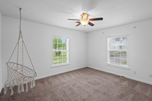 carpeted spare room featuring baseboards and ceiling fan