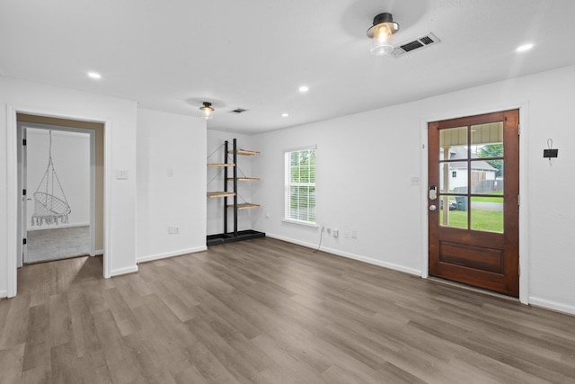 unfurnished living room featuring wood finished floors, visible vents, and a healthy amount of sunlight