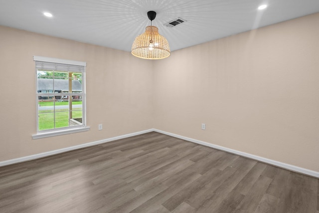 spare room featuring recessed lighting, an inviting chandelier, wood finished floors, visible vents, and baseboards