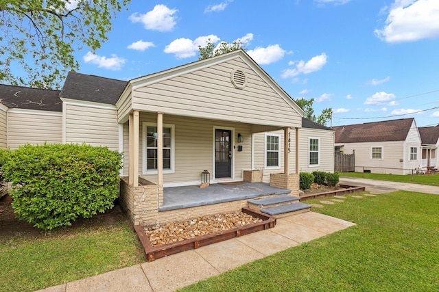 view of front of property featuring roof with shingles, a front yard, and covered porch