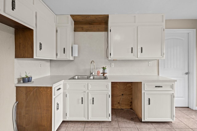 kitchen with light tile patterned floors, white cabinetry, a sink, and light countertops