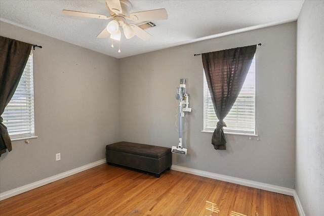 empty room featuring hardwood / wood-style flooring, plenty of natural light, ceiling fan, and a textured ceiling