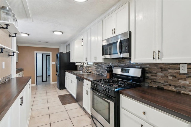 kitchen featuring sink, light tile patterned flooring, decorative backsplash, white cabinets, and appliances with stainless steel finishes