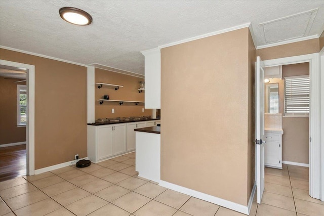 kitchen with white cabinets, light tile patterned floors, and ornamental molding