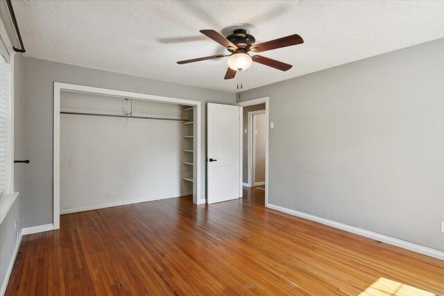 unfurnished bedroom featuring a textured ceiling, a closet, hardwood / wood-style flooring, and ceiling fan