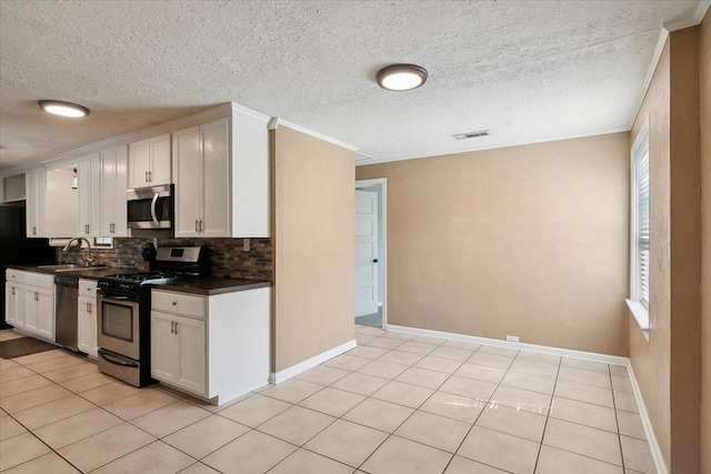 kitchen with appliances with stainless steel finishes, white cabinetry, and light tile patterned flooring