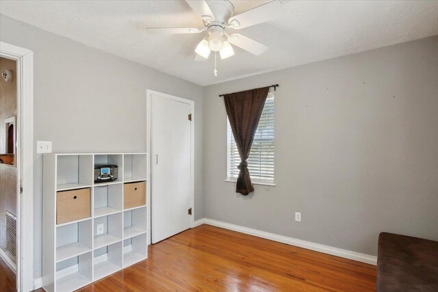 unfurnished bedroom with hardwood / wood-style floors, ceiling fan, and a textured ceiling